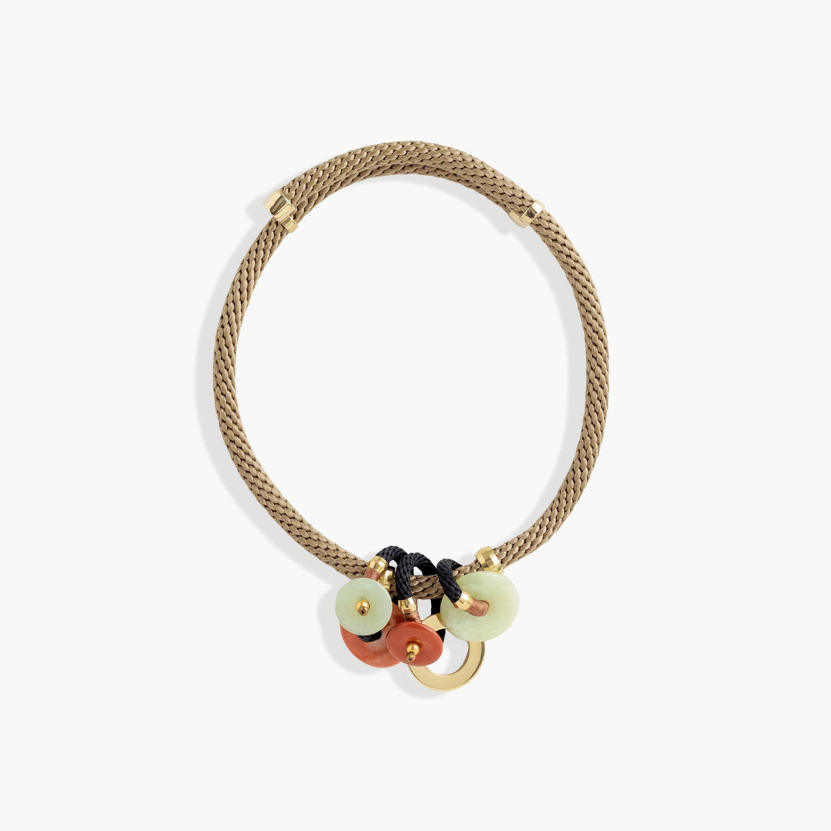 A braided beige rope necklace with gold-toned hardware and three dangling charms: two pale green circular discs, one terracotta orange circular disc, and a small gold ring, shown on a light gray background.
