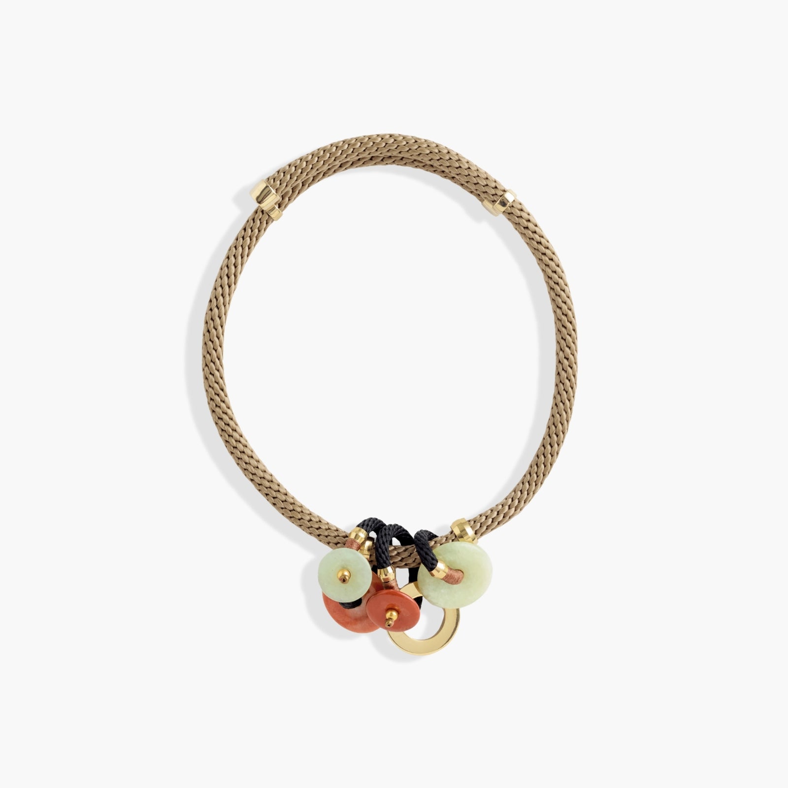 A braided beige rope necklace with gold-toned hardware and three dangling charms: two pale green circular discs, one terracotta orange circular disc, and a small gold ring, shown on a light gray background.